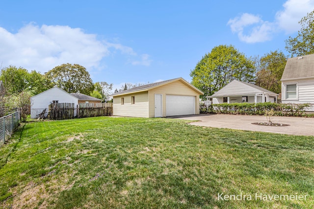 view of yard with a garage, fence, and an outbuilding