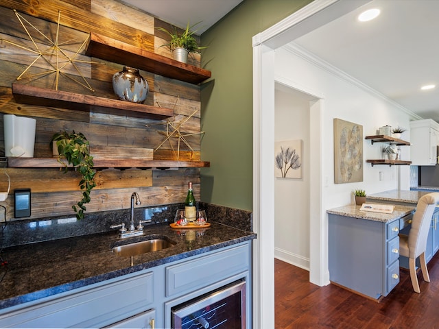 bar featuring ornamental molding, wine cooler, indoor wet bar, dark wood-type flooring, and a sink