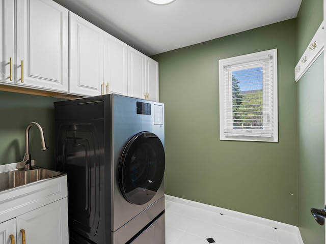 clothes washing area with cabinet space, baseboards, a sink, and washer / clothes dryer