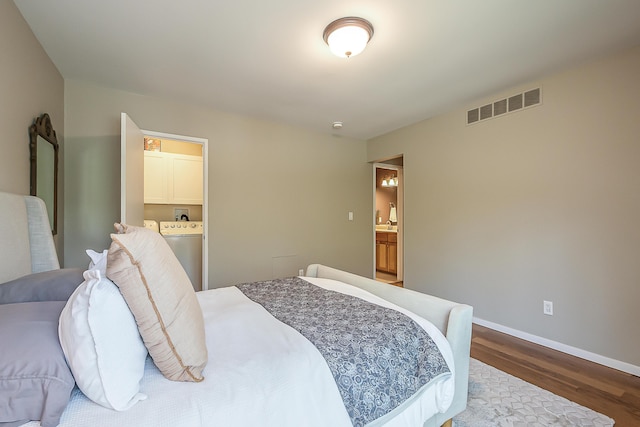 bedroom with visible vents, dark wood finished floors, baseboards, washer / dryer, and ensuite bath