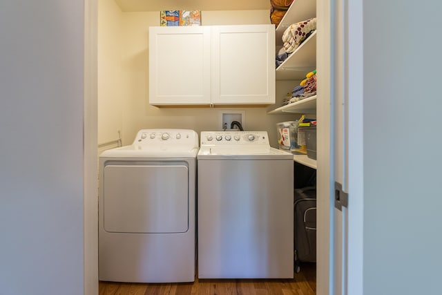 clothes washing area featuring cabinet space, separate washer and dryer, and wood finished floors
