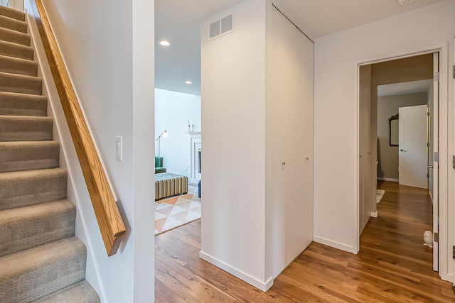 corridor featuring light wood-style floors, stairs, recessed lighting, baseboards, and visible vents