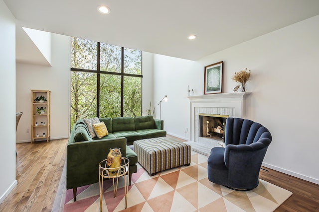 living room with a brick fireplace, recessed lighting, and wood finished floors