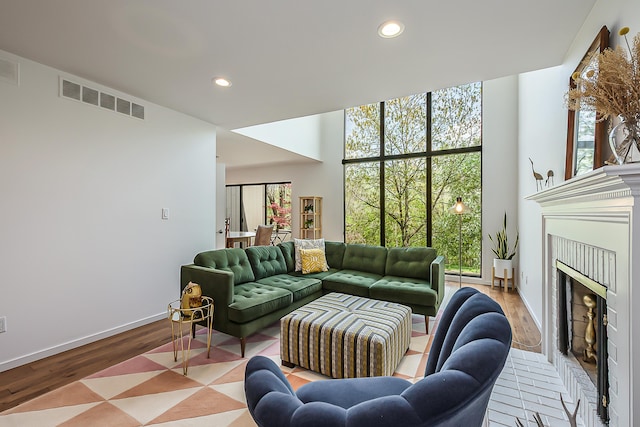 living area featuring visible vents, a fireplace, wood finished floors, baseboards, and recessed lighting