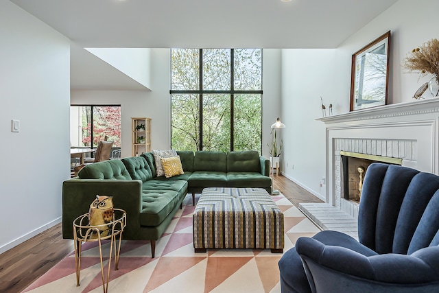 living room with baseboards, a brick fireplace, and wood finished floors