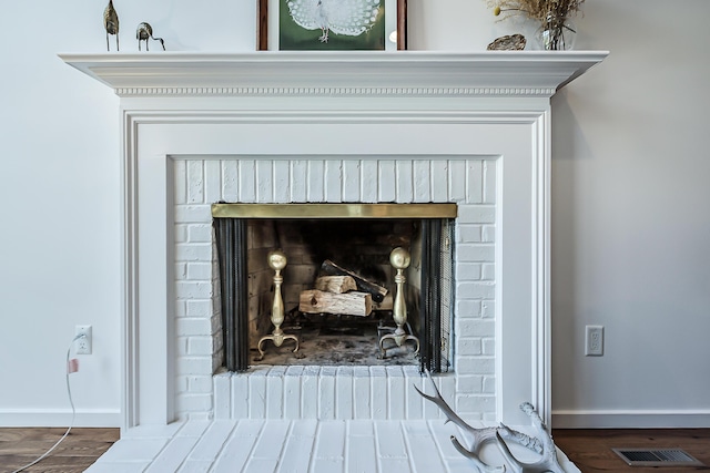 details featuring baseboards, a fireplace, wood finished floors, and visible vents