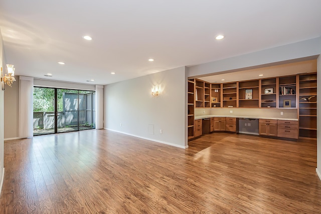 unfurnished living room featuring an inviting chandelier, baseboards, recessed lighting, and wood finished floors