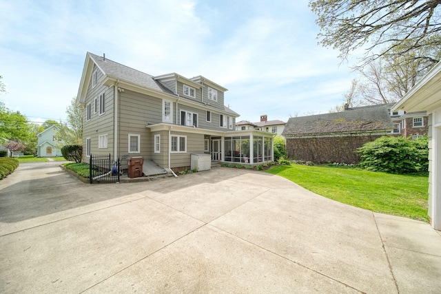 206 S Webster St, Jackson, MI 49203 - back of house featuring a sunroom, a lawn, and a patio area