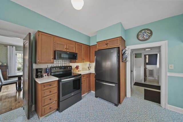 206 S Webster St, Jackson, MI 49203 - kitchen featuring brown cabinets, stainless steel electric range oven, black microwave, light countertops, and freestanding refrigerator