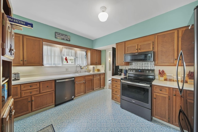 206 S Webster St, Jackson, MI 49203 - kitchen featuring backsplash, appliances with stainless steel finishes, brown cabinets, a sink, and light countertops