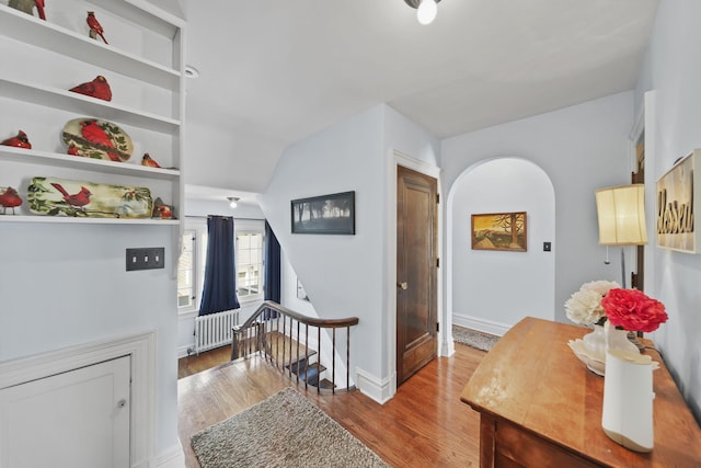 206 S Webster St, Jackson, MI 49203 - interior space with arched walkways, radiator heating unit, baseboards, an upstairs landing, and wood finished floors