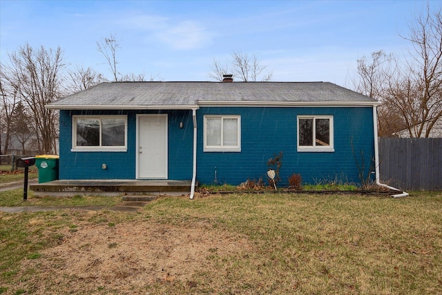view of front facade featuring fence, roof with shingles, and a front yard