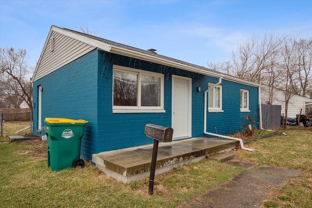 view of front facade featuring brick siding, a front lawn, and fence