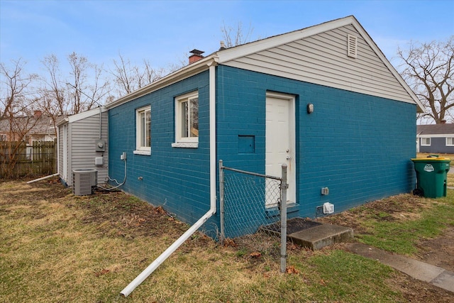view of property exterior with central air condition unit, fence, a chimney, and a yard