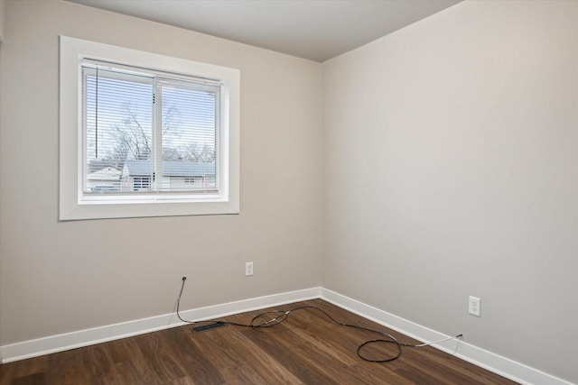 unfurnished room with baseboards, dark wood-style floors, and visible vents