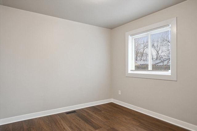 empty room with visible vents, baseboards, and dark wood finished floors