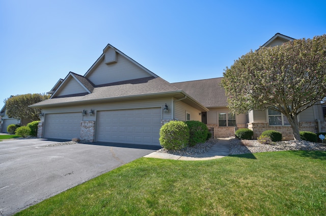 view of front of house featuring a garage, a front yard, roof with shingles, brick siding, and driveway