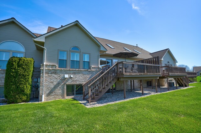 back of property featuring stairs, a lawn, a wooden deck, and brick siding