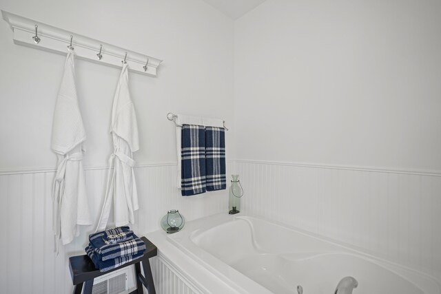 bathroom featuring a garden tub and a wainscoted wall