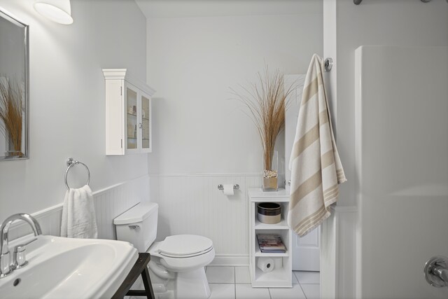 bathroom featuring a sink, tile patterned floors, wainscoting, and toilet