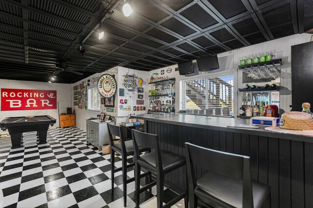 bar featuring rail lighting, wet bar, and tile patterned floors