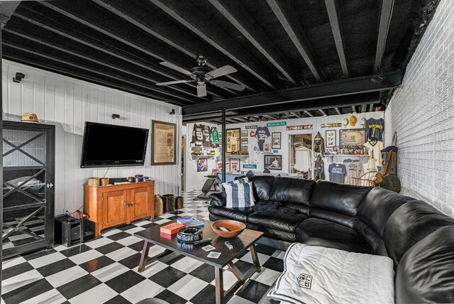 living area with wooden walls, tile patterned floors, and ceiling fan