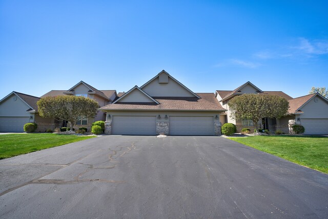 single story home featuring a garage, a front yard, driveway, and stone siding