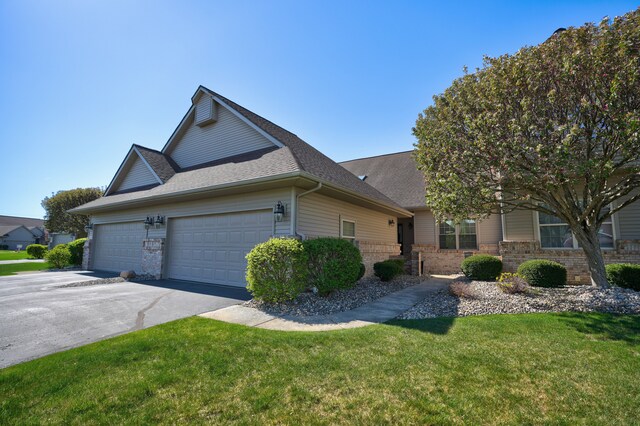 view of front of house featuring a garage, a front lawn, roof with shingles, brick siding, and driveway