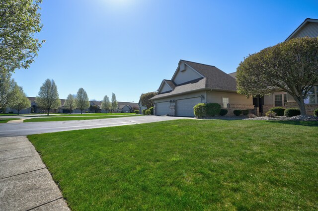 view of side of property with a lawn, an attached garage, roof with shingles, and concrete driveway
