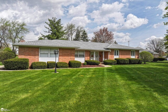 ranch-style house with brick siding, a chimney, and a front lawn