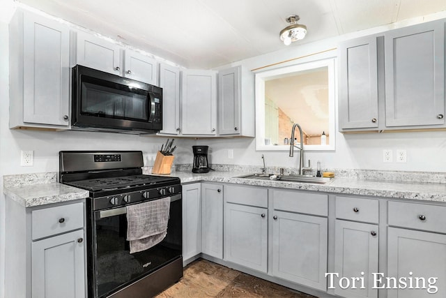 kitchen featuring a sink, gray cabinets, light stone countertops, and black appliances