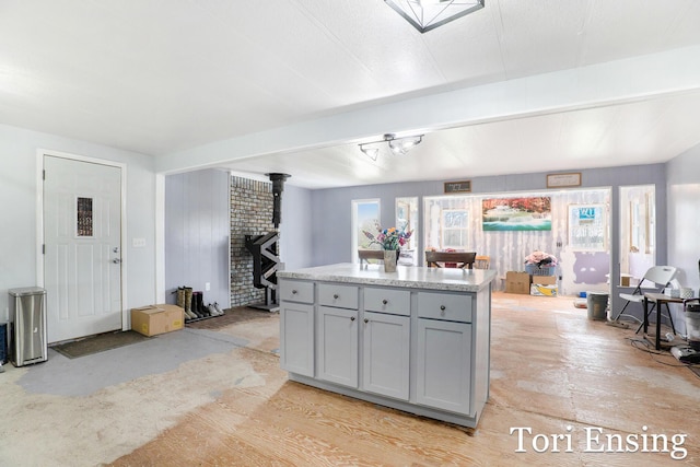 kitchen with gray cabinetry, a kitchen island, and a wood stove