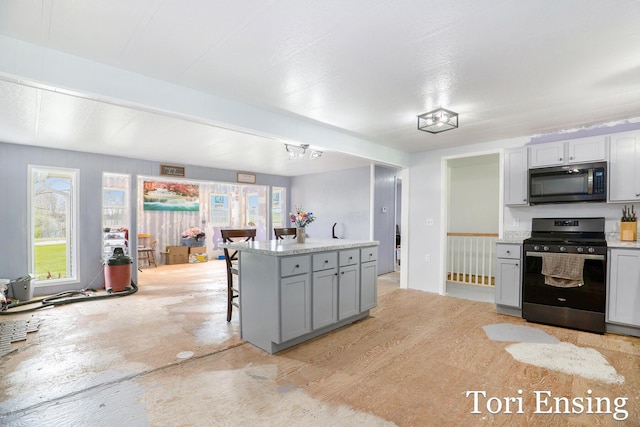 kitchen with appliances with stainless steel finishes, a kitchen island, a breakfast bar area, and gray cabinetry