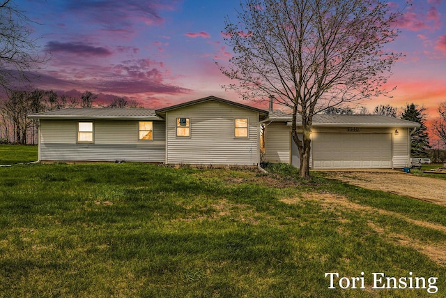view of front of property featuring an attached garage, dirt driveway, a yard, and metal roof