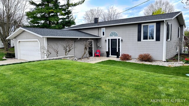 split level home with an attached garage, a chimney, a shingled roof, and a front lawn