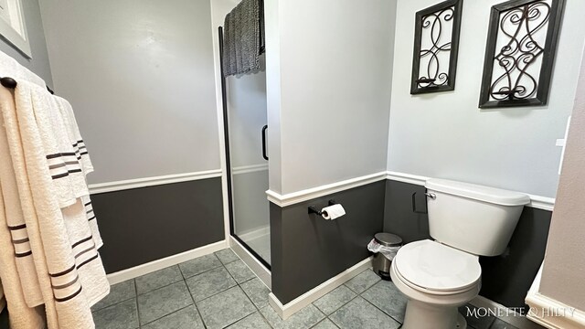 bathroom featuring toilet, a shower stall, and tile patterned flooring