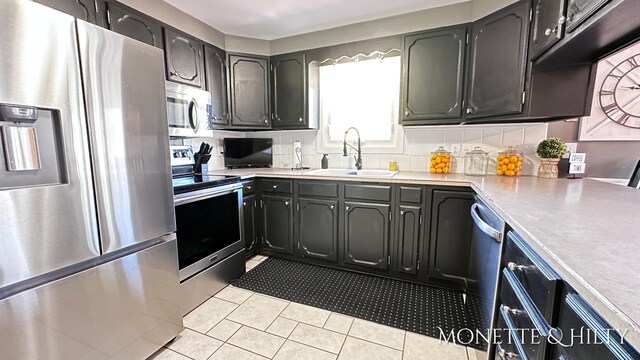 kitchen with light tile patterned flooring, appliances with stainless steel finishes, a sink, light countertops, and tasteful backsplash