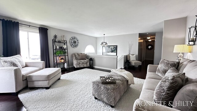 living area with an inviting chandelier, baseboards, wood finished floors, and a healthy amount of sunlight
