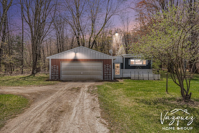 12480 Fargo St NE, Gowen, MI 49326 - garage at dusk with a garage, dirt driveway, and a yard