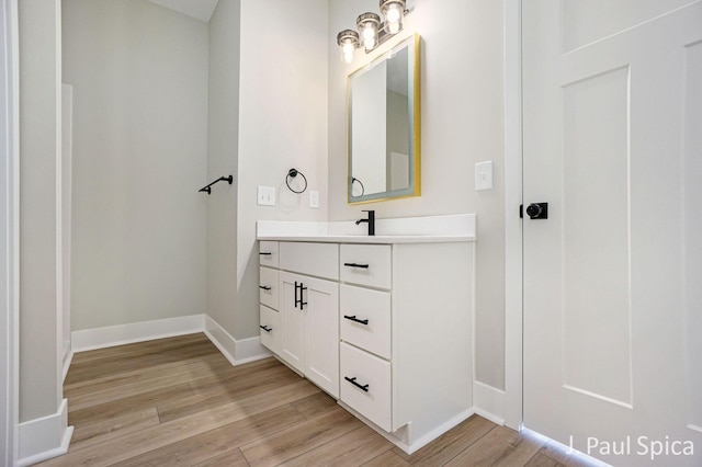 bathroom featuring baseboards, wood finished floors, and vanity