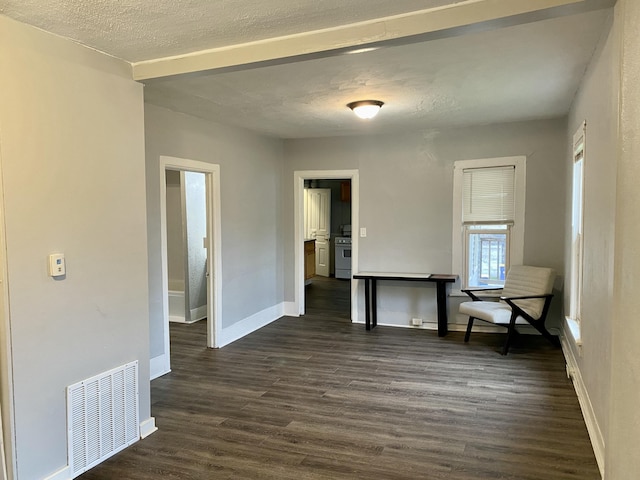 unfurnished dining area featuring dark wood-style flooring, baseboards, visible vents, and a textured ceiling