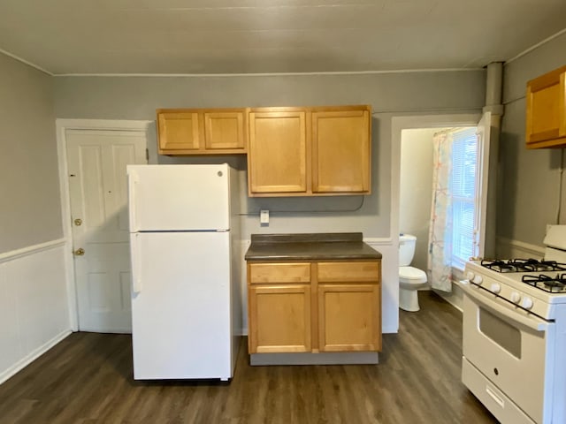 kitchen with dark countertops, white appliances, and dark wood-type flooring