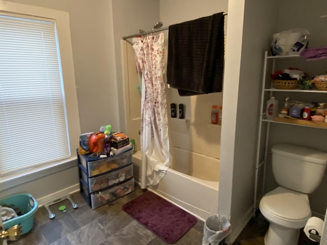 full bath featuring baseboards, shower / bath combo, and toilet