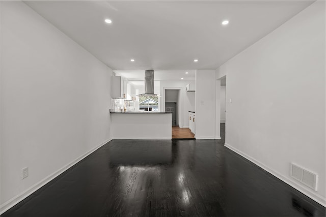 unfurnished living room featuring dark wood-style flooring, visible vents, baseboards, ornate columns, and recessed lighting