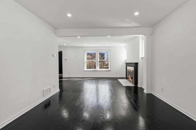 unfurnished living room featuring visible vents, recessed lighting, a fireplace with flush hearth, and dark wood-type flooring