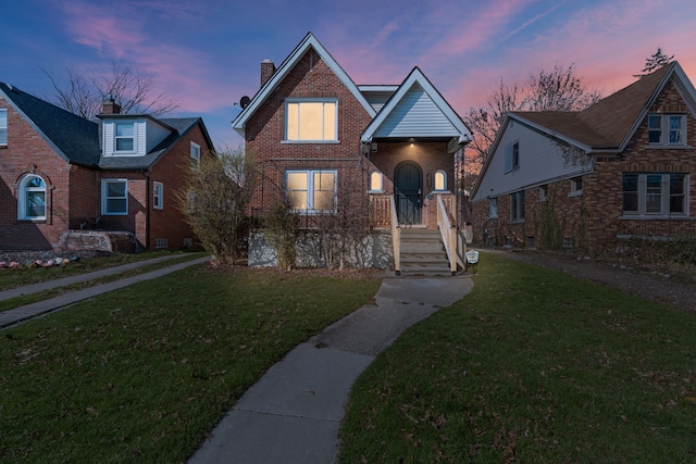 view of front facade with a yard, brick siding, and a chimney
