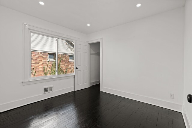 spare room featuring visible vents, recessed lighting, baseboards, and dark wood-style flooring