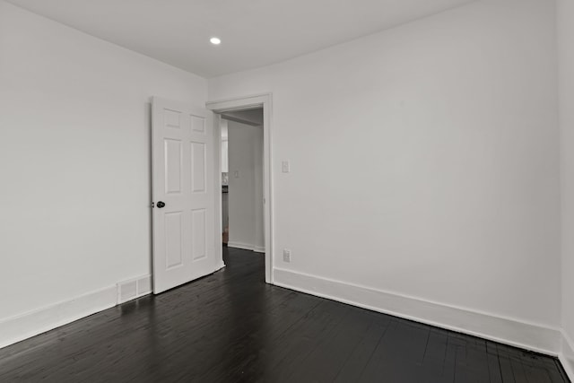 empty room featuring recessed lighting, baseboards, dark wood finished floors, and visible vents