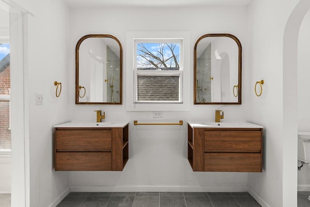 full bathroom with a sink, baseboards, and two vanities