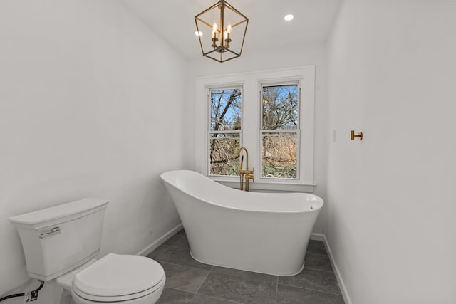 bathroom with a freestanding bath, toilet, a chandelier, recessed lighting, and baseboards